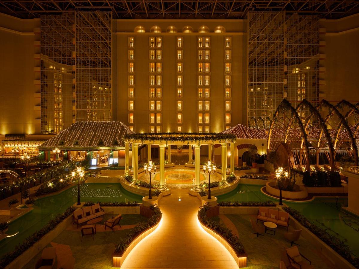 Grand Nikko Tokyo Bay Maihama Ξενοδοχείο Urayasu Εξωτερικό φωτογραφία The photo shows a beautifully illuminated indoor space resembling a luxury hotel or resort. There are elegant architectural features, including large columns, arches, and decorative lighting. The area is designed with lush greenery and well-maintaine