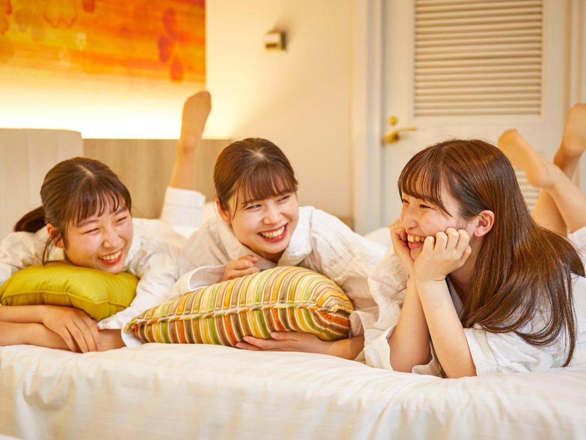 Grand Nikko Tokyo Bay Maihama Ξενοδοχείο Urayasu Εξωτερικό φωτογραφία The photo shows three young women lounging together in a cozy indoor setting. They are dressed in white robes and appear to be relaxed and enjoying each other's company. The women are lying on a bed, with two of them resting on their arms and the thi