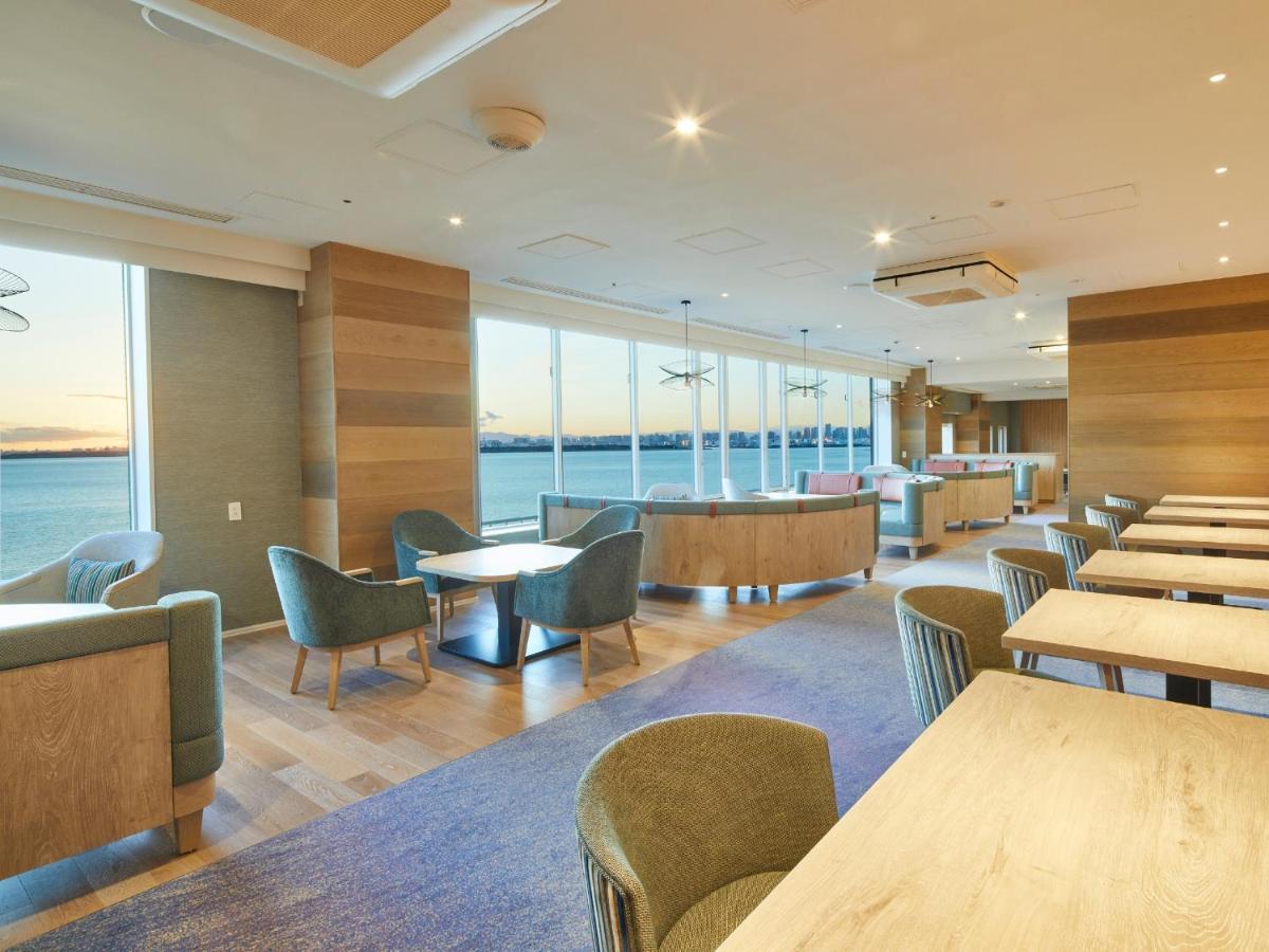 Grand Nikko Tokyo Bay Maihama Ξενοδοχείο Urayasu Εξωτερικό φωτογραφία The photo shows a modern interior space, likely a dining or lounge area. It features large windows that offer a view of the water, allowing natural light to fill the room. The decor includes wooden walls and stylish, comfortable furniture, with sever