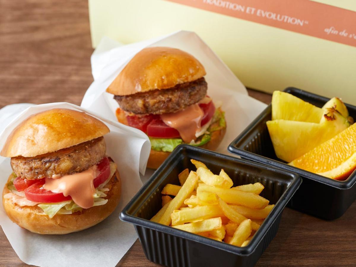 Grand Nikko Tokyo Bay Maihama Ξενοδοχείο Urayasu Εξωτερικό φωτογραφία The photo shows two small burgers placed on a white background, each with a golden-brown bun, a fried patty, lettuce, tomato, and a creamy sauce. Alongside the burgers, there are two containers: one holding a serving of french fries and the other con