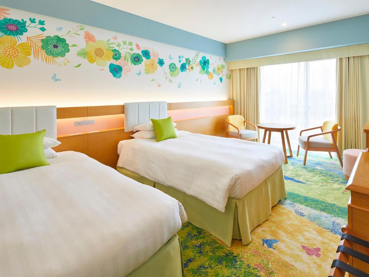 Grand Nikko Tokyo Bay Maihama Ξενοδοχείο Urayasu Εξωτερικό φωτογραφία The photo shows a brightly decorated hotel room featuring two twin beds with white linens and light green accents. Above the beds is a colorful floral mural that adds a cheerful touch to the space. There is a small table and chairs by the window, whi
