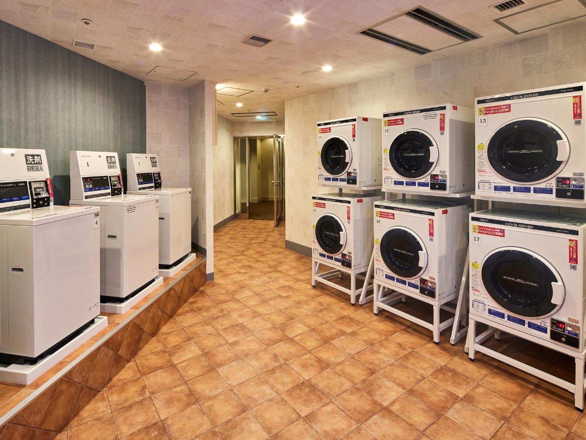 Grand Nikko Tokyo Bay Maihama Ξενοδοχείο Urayasu Εξωτερικό φωτογραφία The photo shows a laundry room with several washing machines and dryers. On the left side, there are five white washing machines, and on the right side, there are four dryers. The machines are arranged in a clean, tiled space with a neutral-colored w