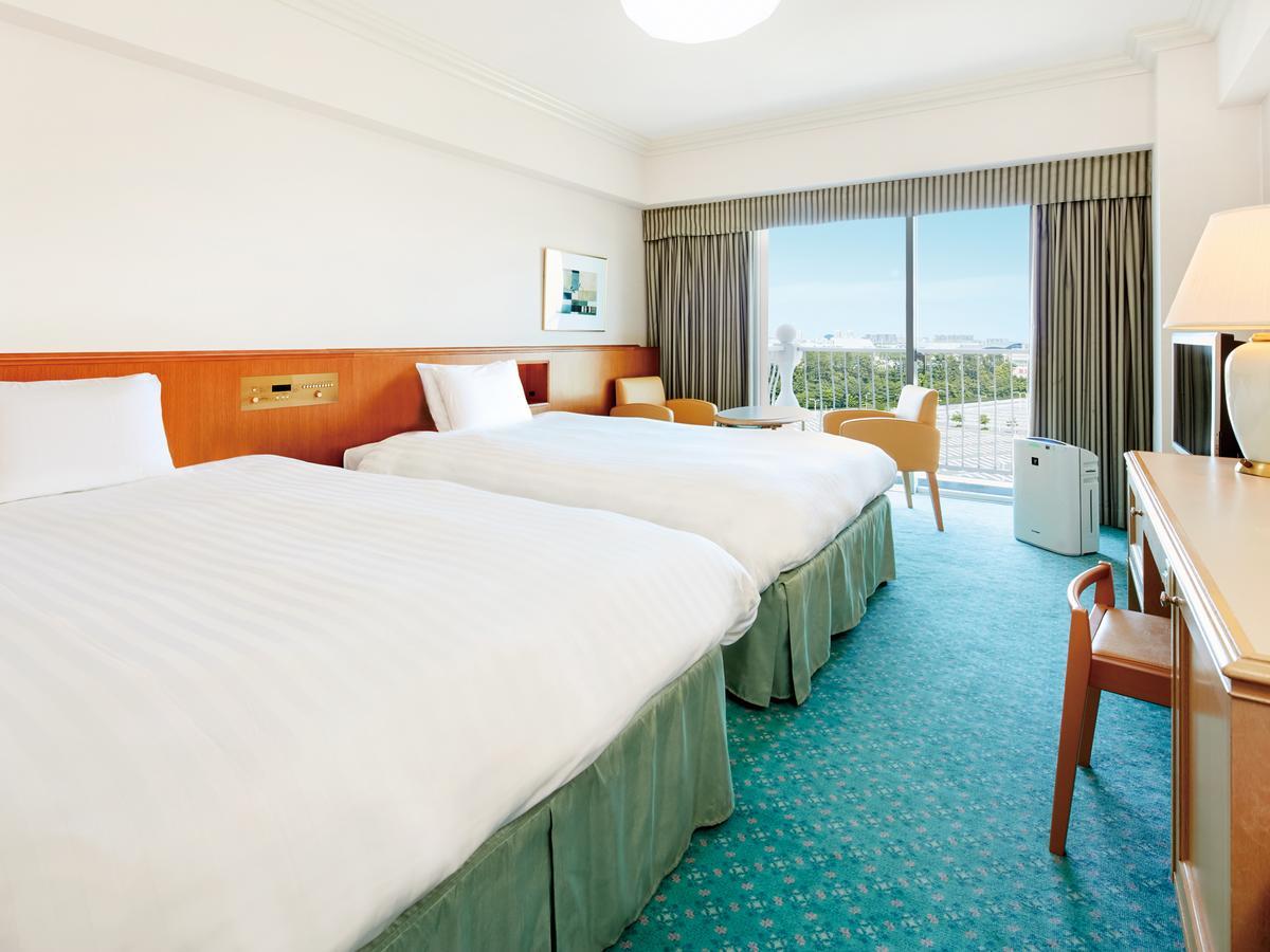 Grand Nikko Tokyo Bay Maihama Ξενοδοχείο Urayasu Εξωτερικό φωτογραφία The photo shows a hotel room featuring two twin beds with white bedding. The walls are painted in light colors, and there’s a window that offers a view outside, letting in natural light. A small table and chairs are visible near the window, as well a